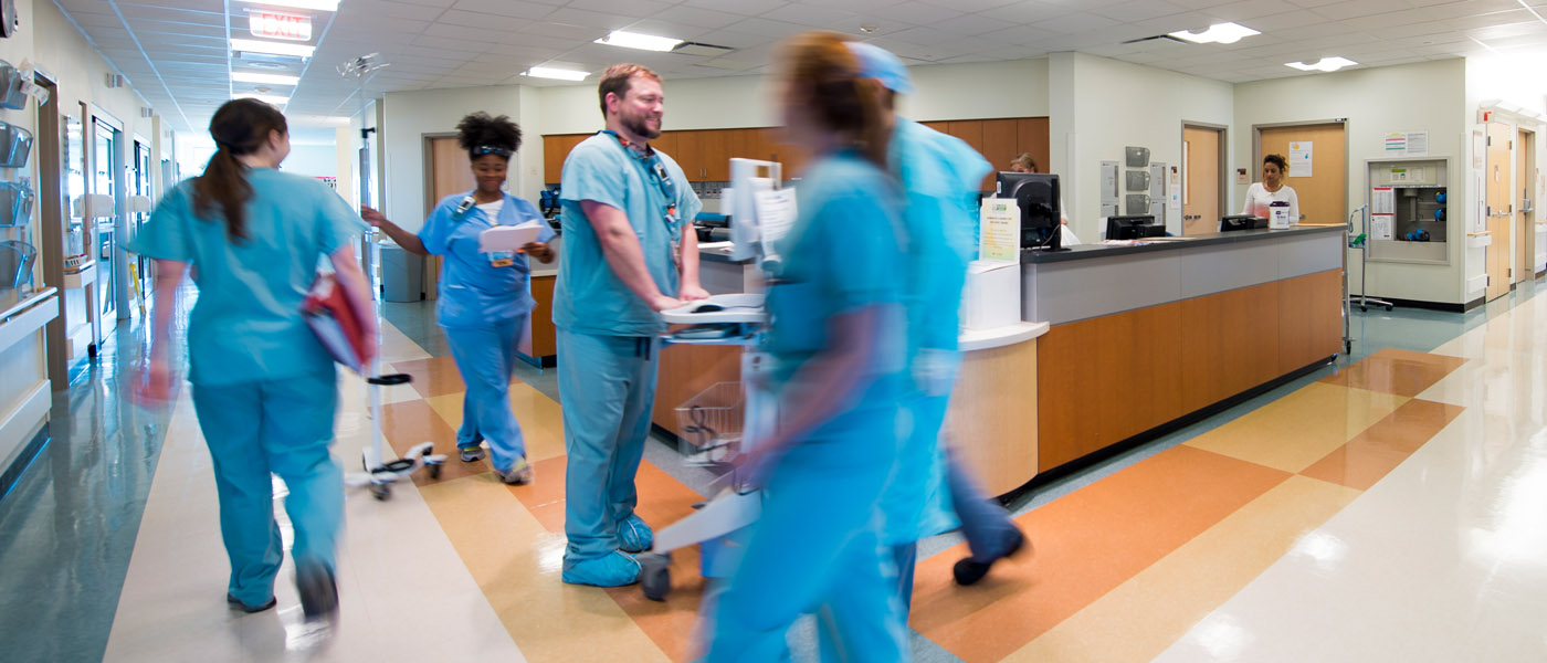 Doctors in scrubs are in motion walking through a hospital hallway